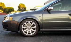 Audi RS6 2003 sedã na cor cinza parado em piso claro mostrando perfil esportivo