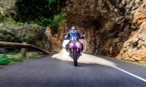 Perfil lateral da Yamaha Tracer 9 rodando em estrada sinuosa com malas rígidas